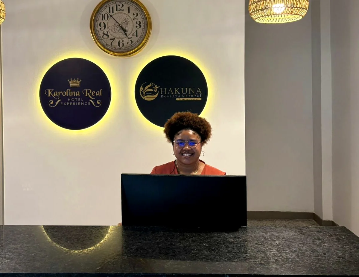 Recepcionista del Hotel Karolina Real atendiendo detrás del mostrador
