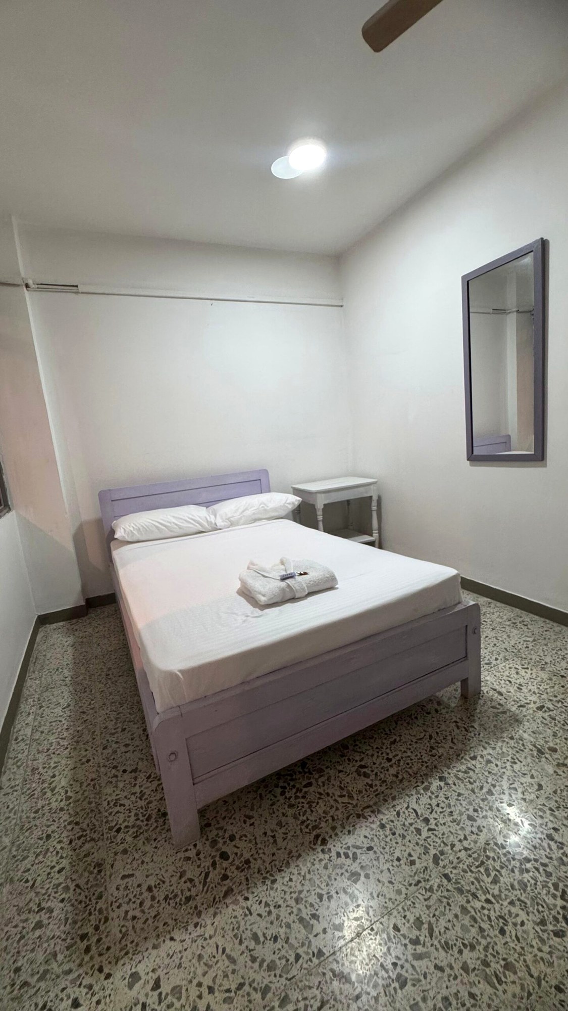 Habitación estándar con una cama, ropa de cama blanca y ventilador de techo