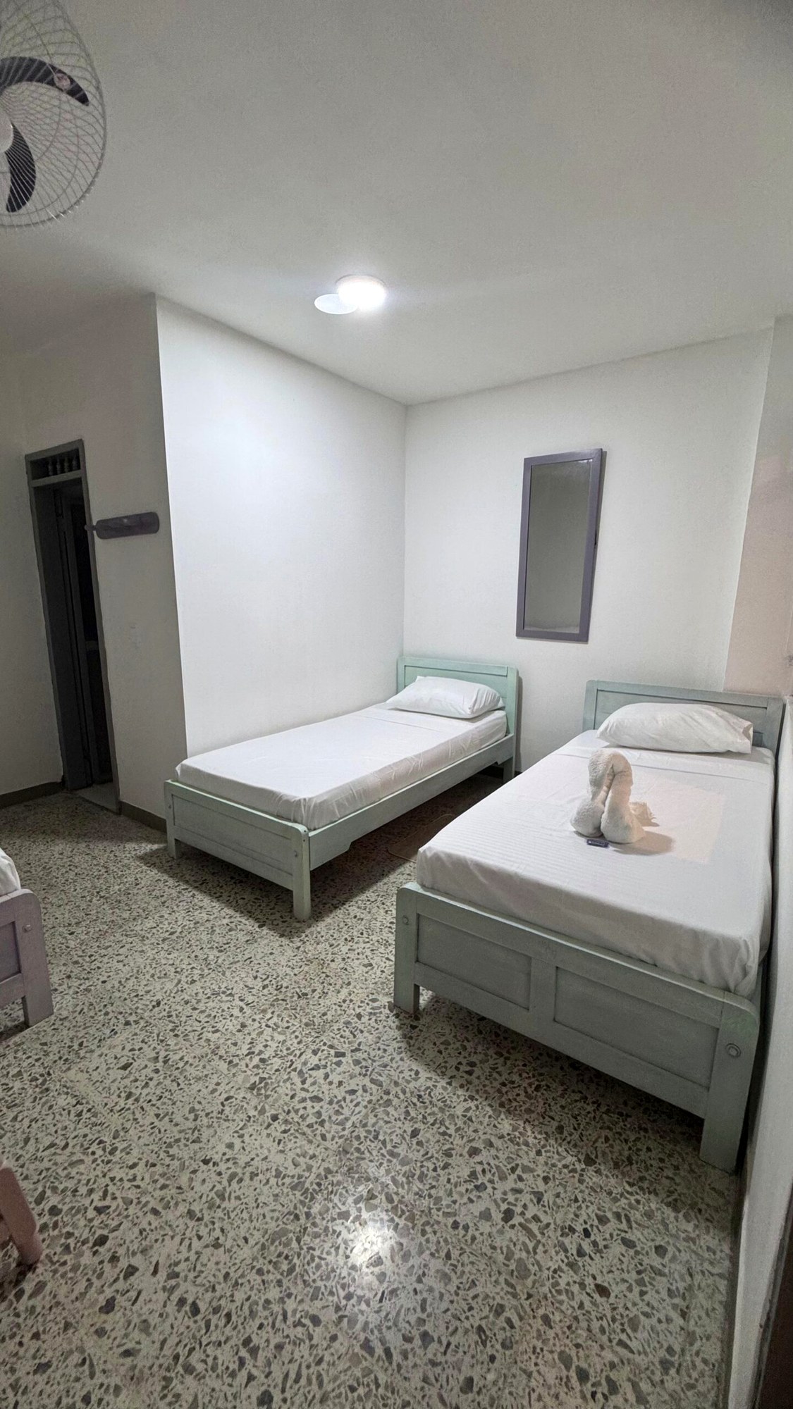 Habitación con dos camas individuales, ropa de cama blanca y ventilador de techo